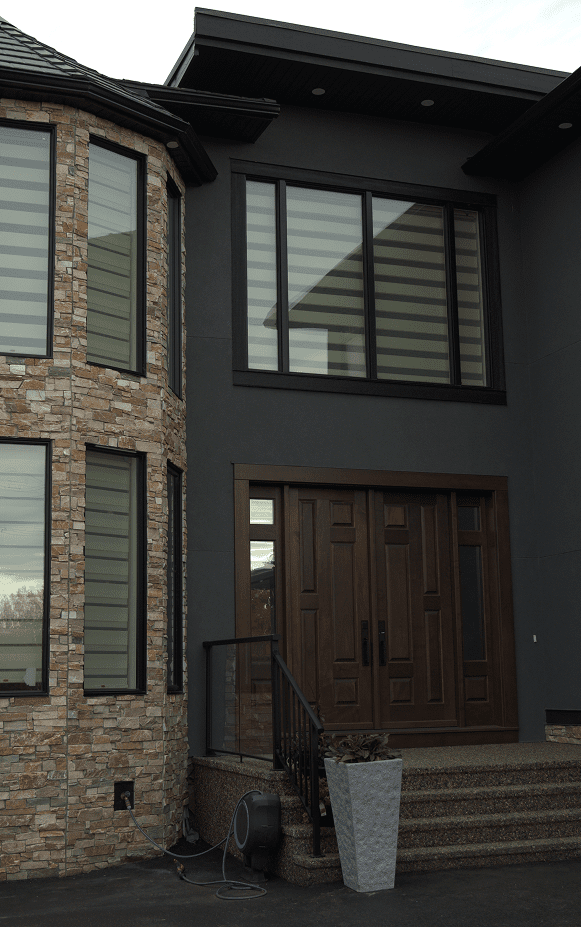 Modern house entrance with large windows and wooden double doors.