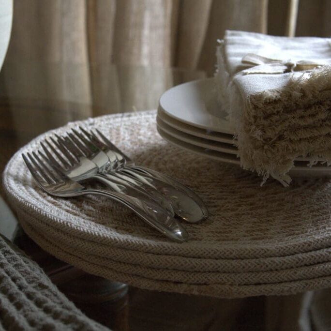Rustic table setting with woven placemats and folded napkins.